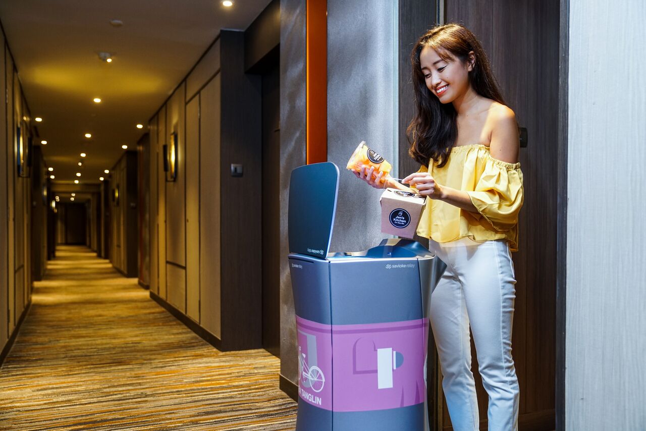 Guest taking delivery by relay robot in Hotel Jen Singapore